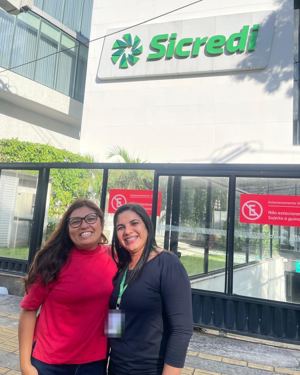 Silvana com uma cliente em frente ao prédio do Sicredi